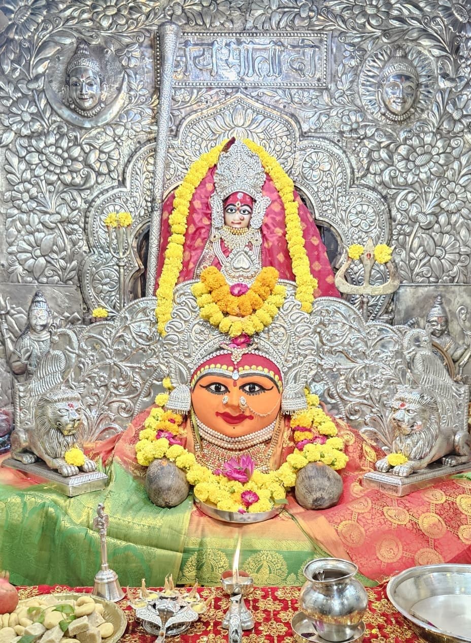 रजत-मण्डित मन्दिर में देवी का मुखौटा एवं प्रतिमा, गेंदे की मालाओं तथा नारियल सहित